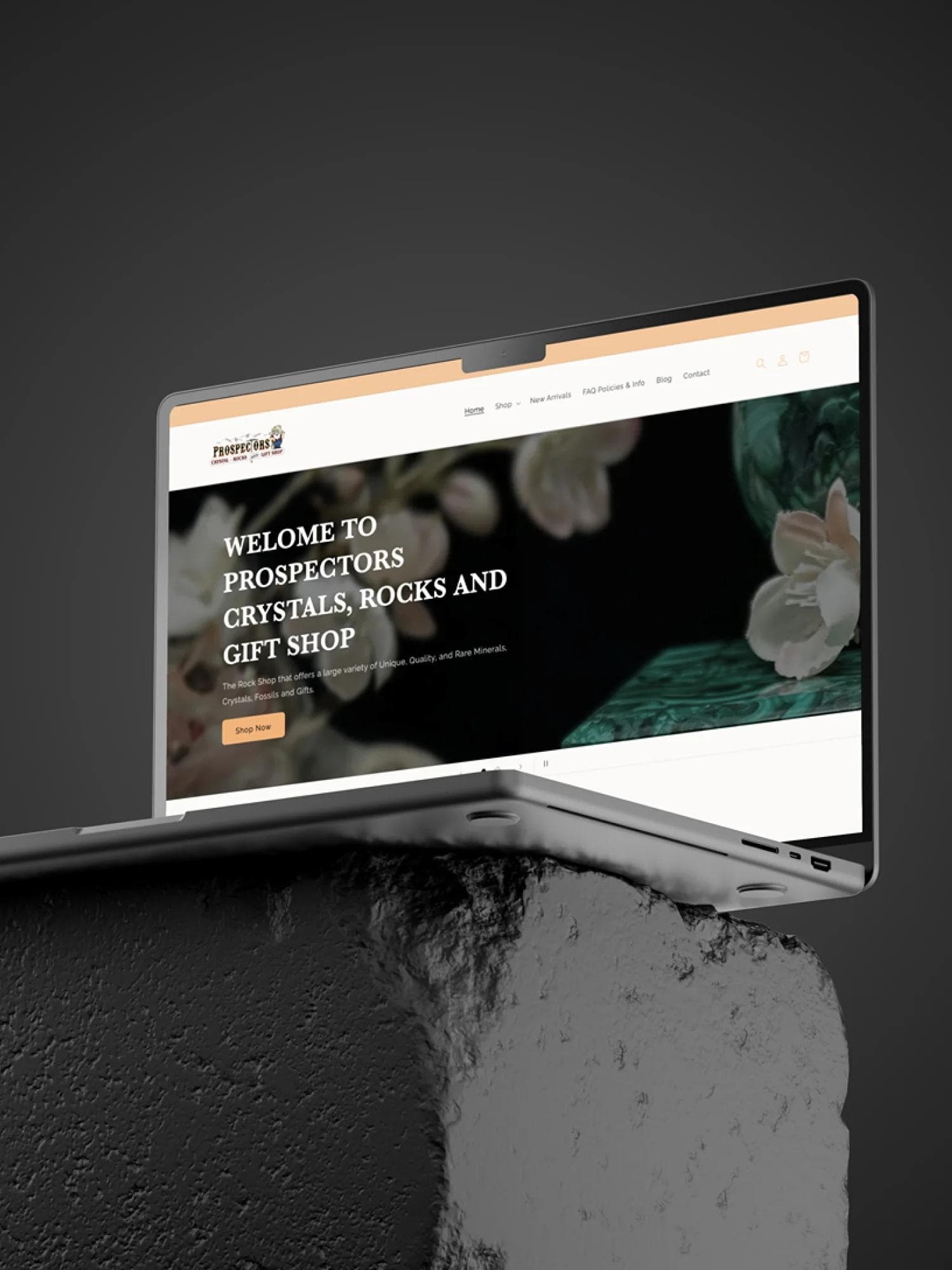 Prospectors Crystals, Rocks & Gift Shop website redesign on a laptop sitting on top of a stone block.
