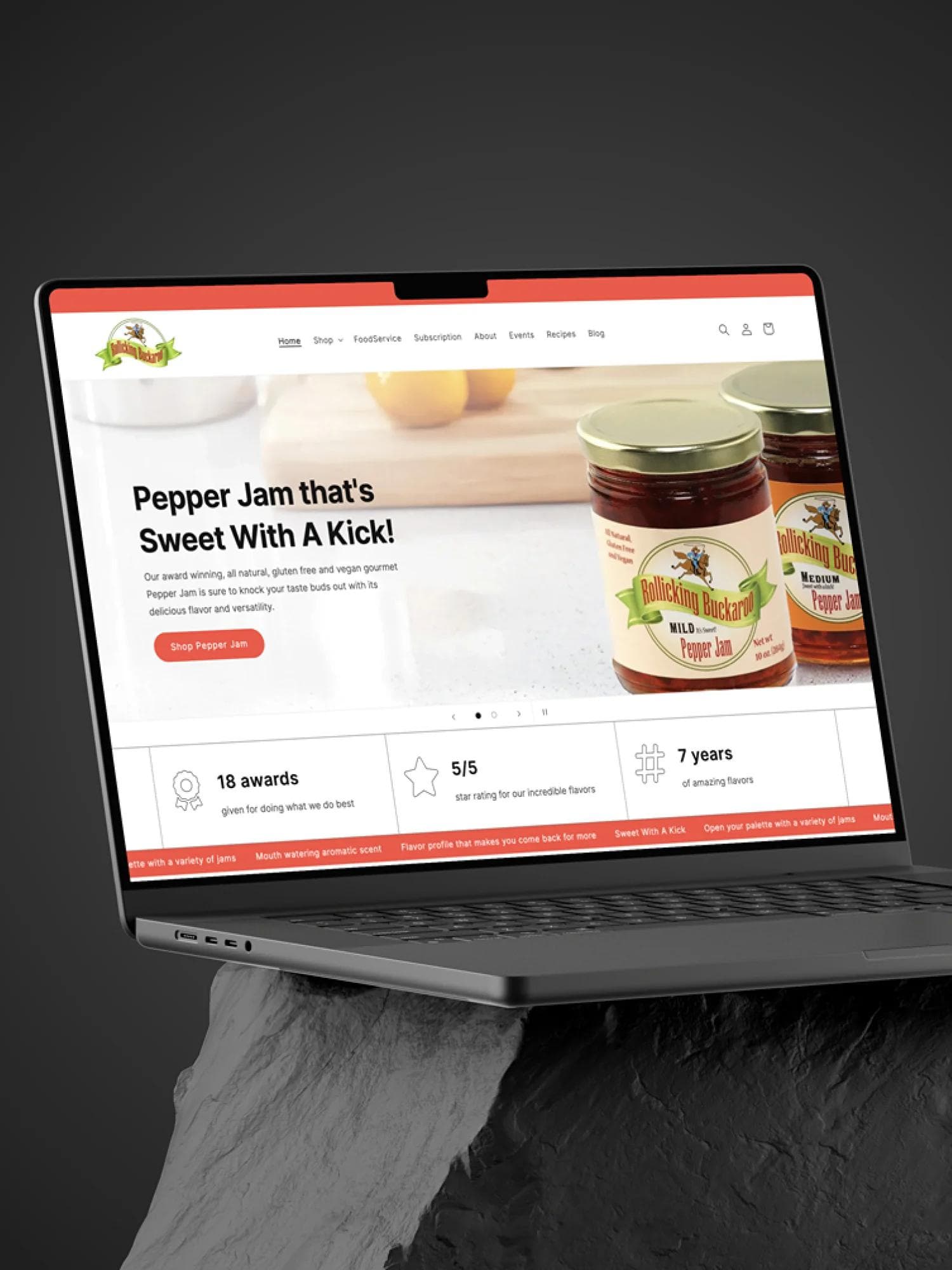 Rollicking Buckaroo Pepper Jam and Seasoning Blends website on a laptop sitting on top of a stone.