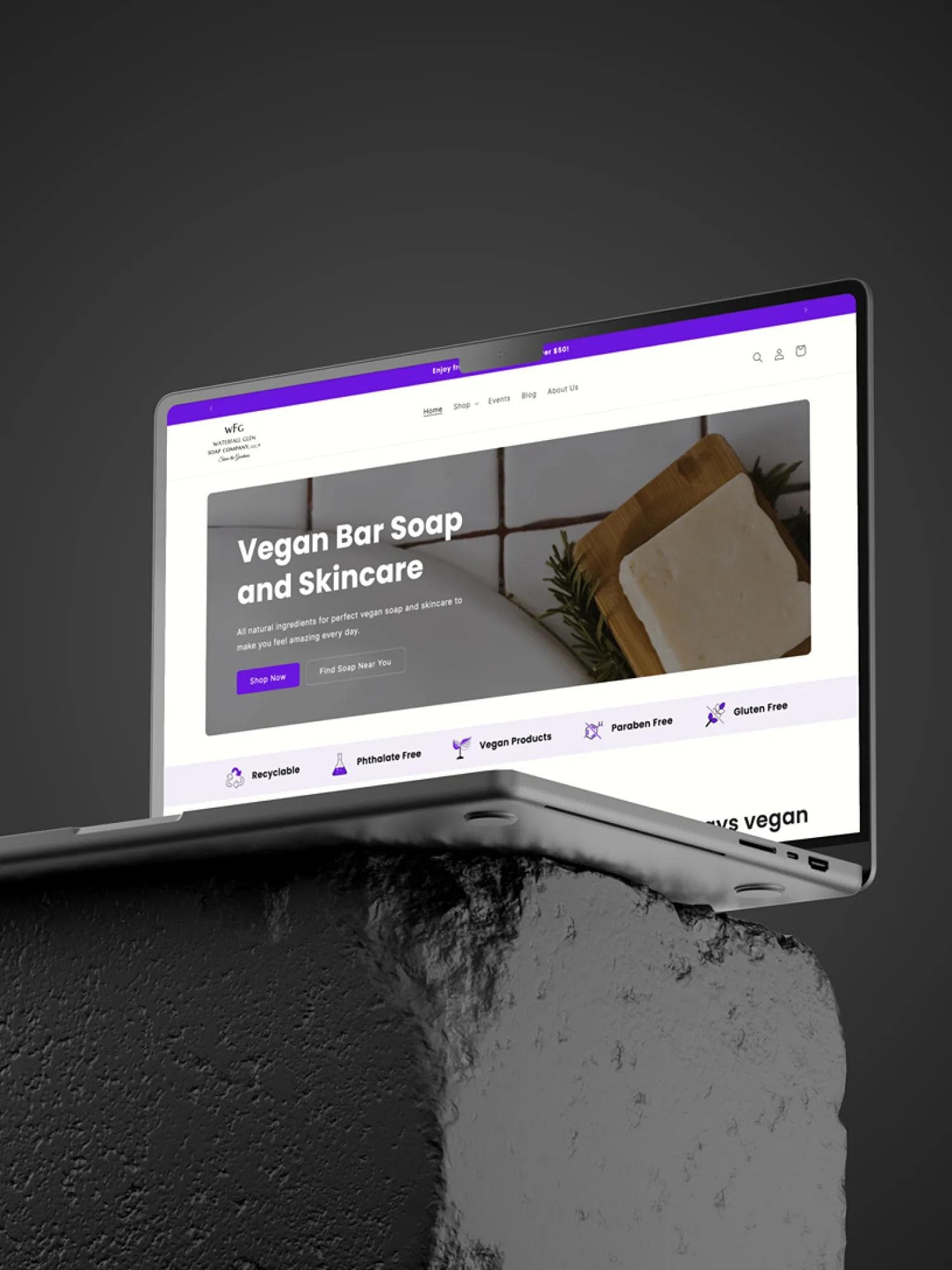 Waterfall glen soap company's website on a laptop sitting on a stone.