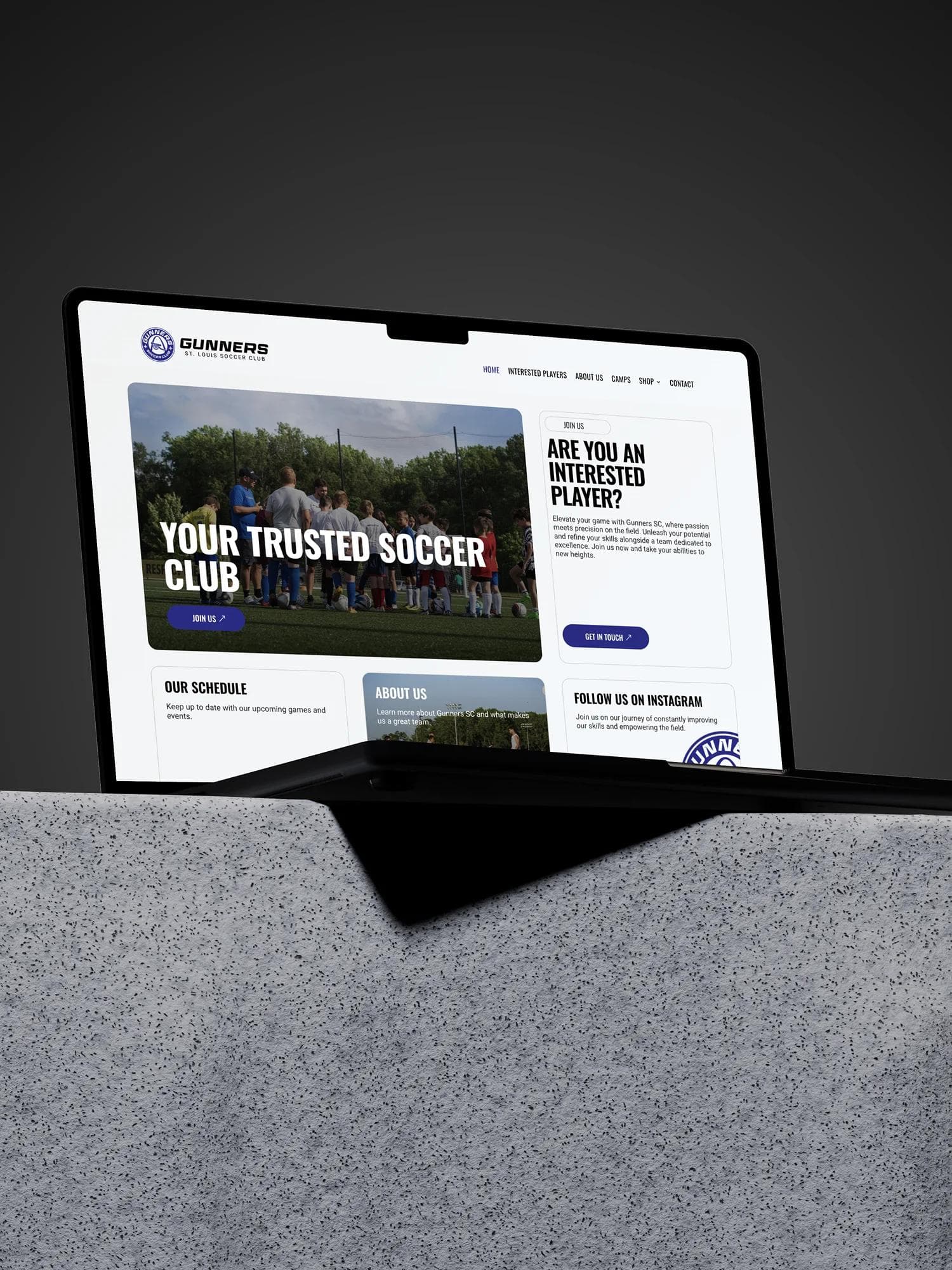 Gunners SC website on a laptop mockup on a stone block.